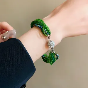 Detailed close-up showing the multi-layer twisted green crystal and seed bead bracelet