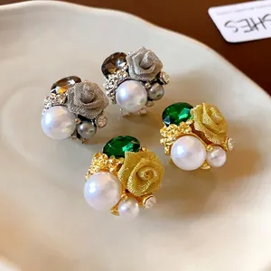 Élégantes boucles d'oreilles à fleurs vintage avec perles et cristaux sur plateau céramique