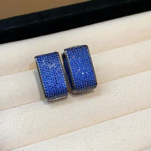 Macro detail of rectangular hoop earrings paved with brilliant blue zircon stones in box.