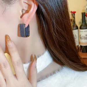 Detailed close-up showing sparkling blue zircon paved geometric hoop earring worn by model
