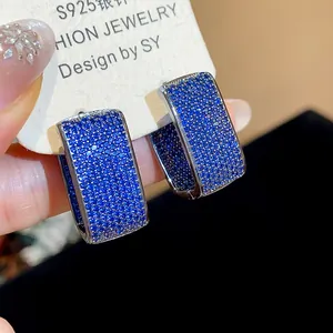 Close-up detail of geometric hoop earrings featuring pavé blue cubic zirconia stones