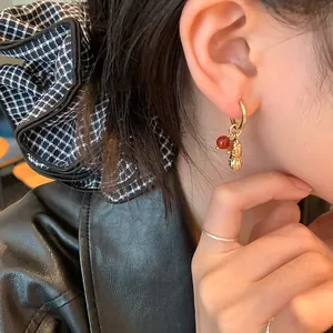 Elegant gold minimalist hoop earrings with red glass beads and a peanut charm decor