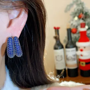 Macro detail of sparkly blue zircon paved geometric earrings in a festive holiday mood