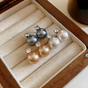 Close-up of elegant pearl earrings in white grey and champagne colors displayed in a box