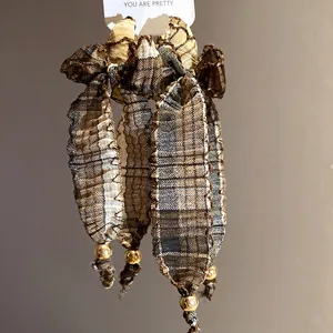 Detailed macro view of vintage brown plaid fabric bow tassel earrings with gold beads