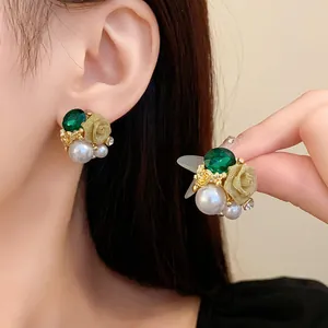 Vue détaillée de boucles d'oreilles rétro avec pierres vertes et roses.