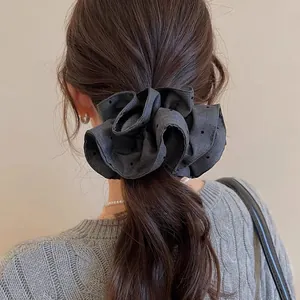 Detailed macro view of a vintage black polka dot fabric scrunchie styled on a ponytail