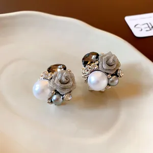 Gros plan détaillé de boucles d'oreilles vintage en argent avec fleur et perle.
