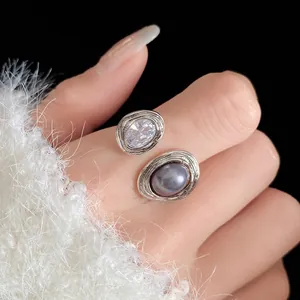Close-up view of an elegant silver-toned oval open ring with clear rhinestone and grey pearl