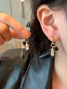 Close-up detail of Korean style gold peanut pendant earrings with black glass beads