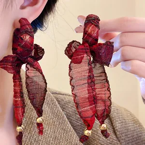 Close-up detail of red plaid fabric bow earrings with gold beads and long tassels