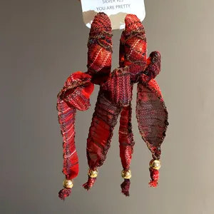 Detailed view of vintage red plaid fabric bow tassel earrings with gold bead accents
