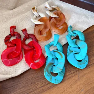 Close-up of colorful irregular acrylic chain link drop earrings on a rustic linen cloth
