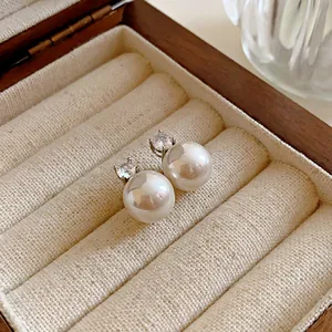 Elegant pearl stud earrings with zircon detail presented in a luxury wooden jewelry box
