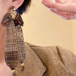 Detailed view of vintage plaid fabric bowtie tassel earrings with gold accents