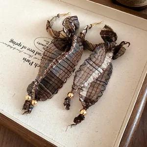 Detailed macro view of vintage plaid fabric bow earrings with elegant gold beads
