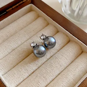 Close-up of elegant grey pearl stud earrings with sparkling zircon in jewelry box