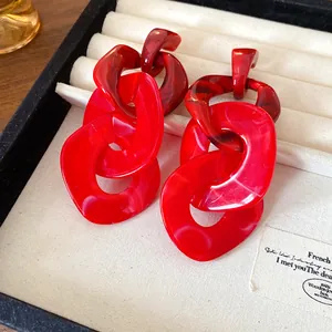 Close-up detail of bold red acrylic chunky chain link drop earrings in a jewelry box