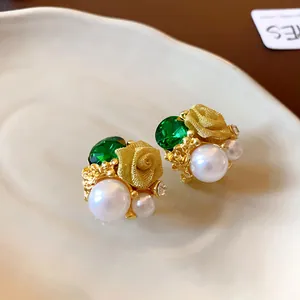 Vue détaillée des boucles d'oreilles vintage avec gemme verte, perle et rose dorée.