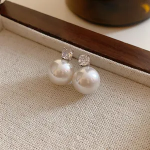 Close-up detail of elegant white pearl stud earrings with sparkling cubic zirconia