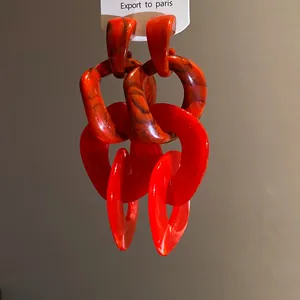Close-up detail of red acrylic irregular chain link earrings with marbled texture.