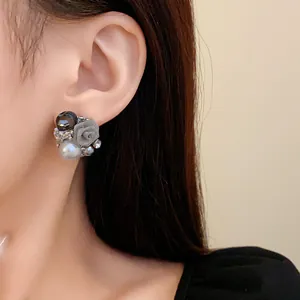 Gros plan sur une boucle d'oreille rétro en argent avec perle et fleur en tissu