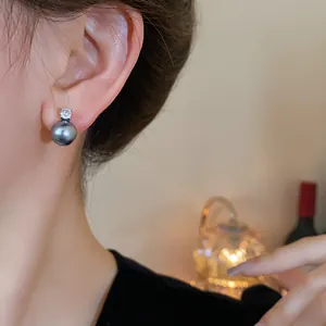Detail of a vintage silver stud earring featuring a dark gray pearl and clear zircon.