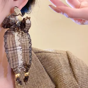 Close-up of vintage fabric bow tassel earrings with gold beads and ethnic pattern