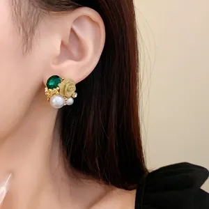 Détail de puce d'oreille vintage française avec pierre verte, rose dorée et perles