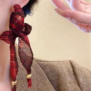 Detailed close-up of retro red fabric bow tassel earrings with gold beads and silver needles