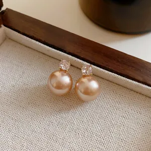Close-up view of elegant vintage champagne pearl stud earrings with sparkling zircon
