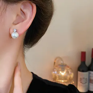 Close-up of elegant pearl and zircon earring worn on a female ear in a warm setting