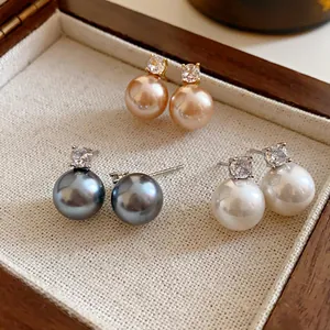 Close-up of vintage pearl earrings with cubic zirconia studs in three elegant colors.