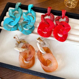 Detailed view of large acrylic chain-link earrings in red, blue, and amber colors