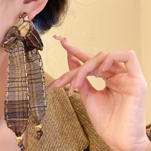 Close-up of retro brown plaid fabric bow earrings featuring elegant gold bead tassels.