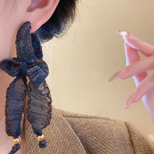 Close-up of vintage fabric bow tassel earring with plaid pattern and gold beads