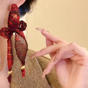 Close-up detail of vintage red plaid fabric bow earrings featuring tassels and gold beads
