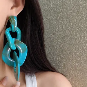 Detailed macro view of oversized turquoise acrylic chain drop earrings with silver needles
