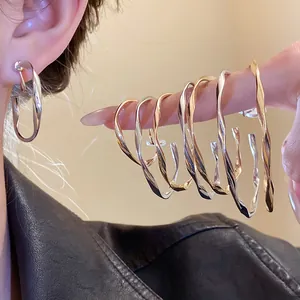 Detailed view of geometric twisted hoop earrings set in elegant gold and silver finishes