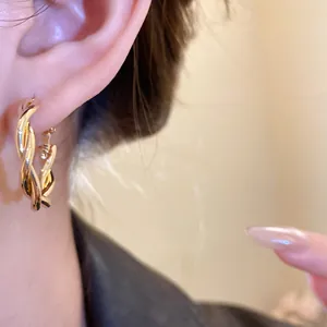 Close-up of elegant gold twisted hoop earring worn on an ear for a stylish look