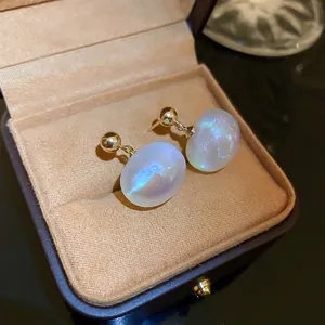 Close-up of iridescent mermaid pearl earrings with gold studs in a jewelry box