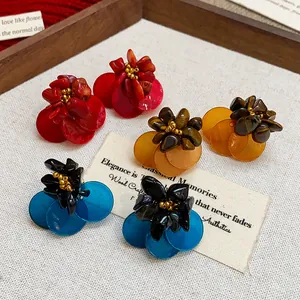 Detail view of retro flower earrings with shell petals and tiger eye stones.