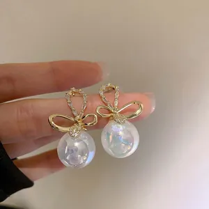 Detailed view of elegant bow earrings with iridescent mermaid pearls and crystals.
