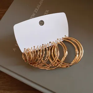 Close-up of golden geometric hoop earring set featuring twisted and smooth textured designs