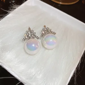 Close-up of elegant rhinestone mermaid pearl stud earrings on white fur background