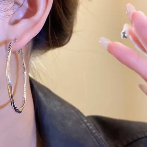 Detail view of elegant silver twisted hoop earrings with irregular geometric texture.