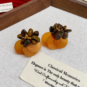 Macro view of vintage tiger eye and amber shell petal stud earrings on fabric background