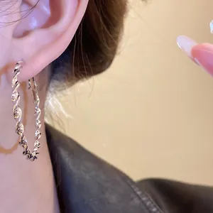Detailed close-up showing the metallic texture of a silver twisted hoop earring on an ear