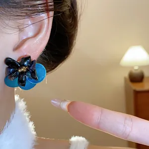 Detailed macro view of vintage blue petal earrings featuring black tiger eye stone center