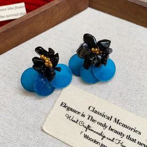 Close-up detail of retro shell tiger eye stone stud earrings with black floral accents